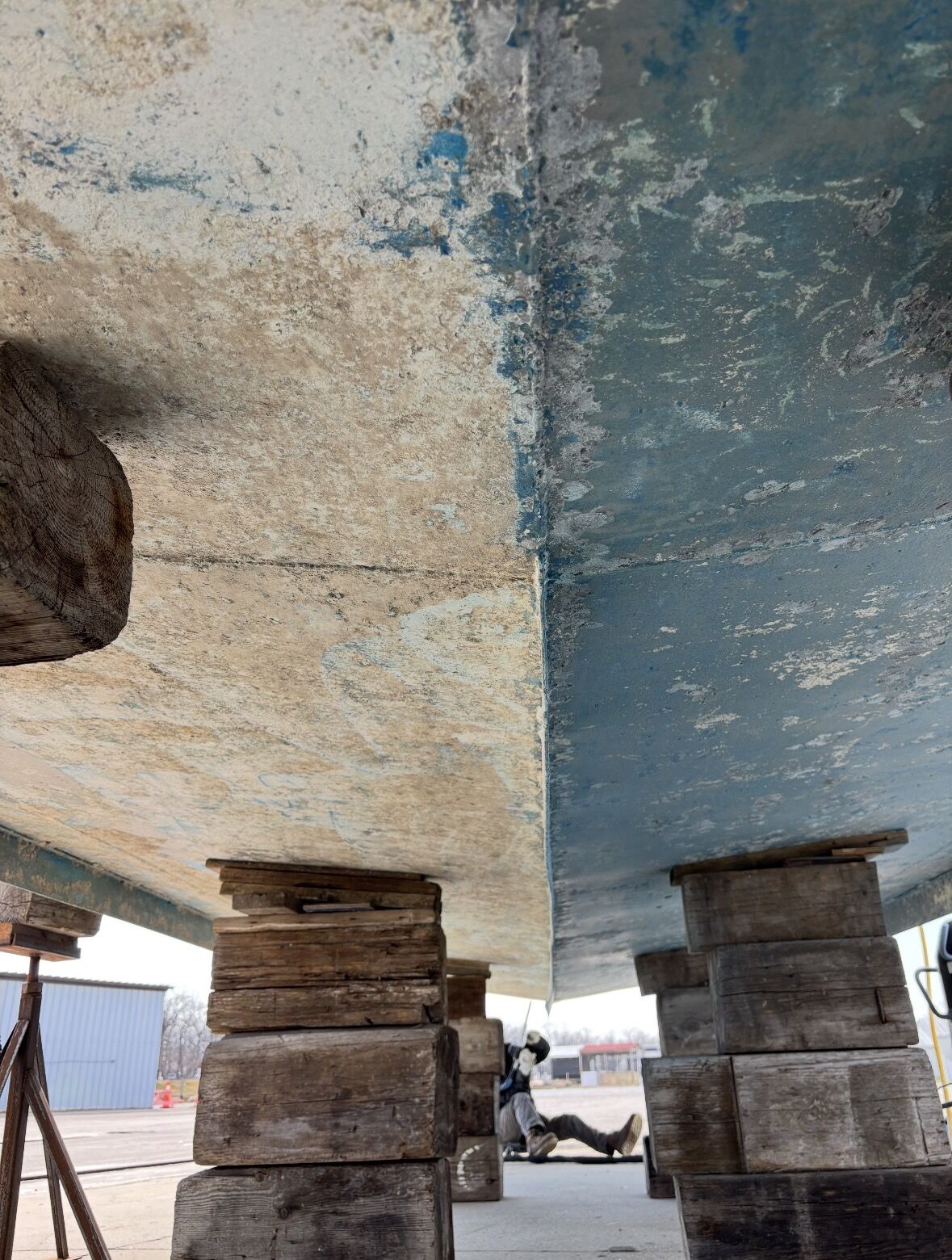 Boat hull cleaned in place by Ontario Dry Ice Blasting — half stripped to bare surface, half still showing blue paint and marine growth