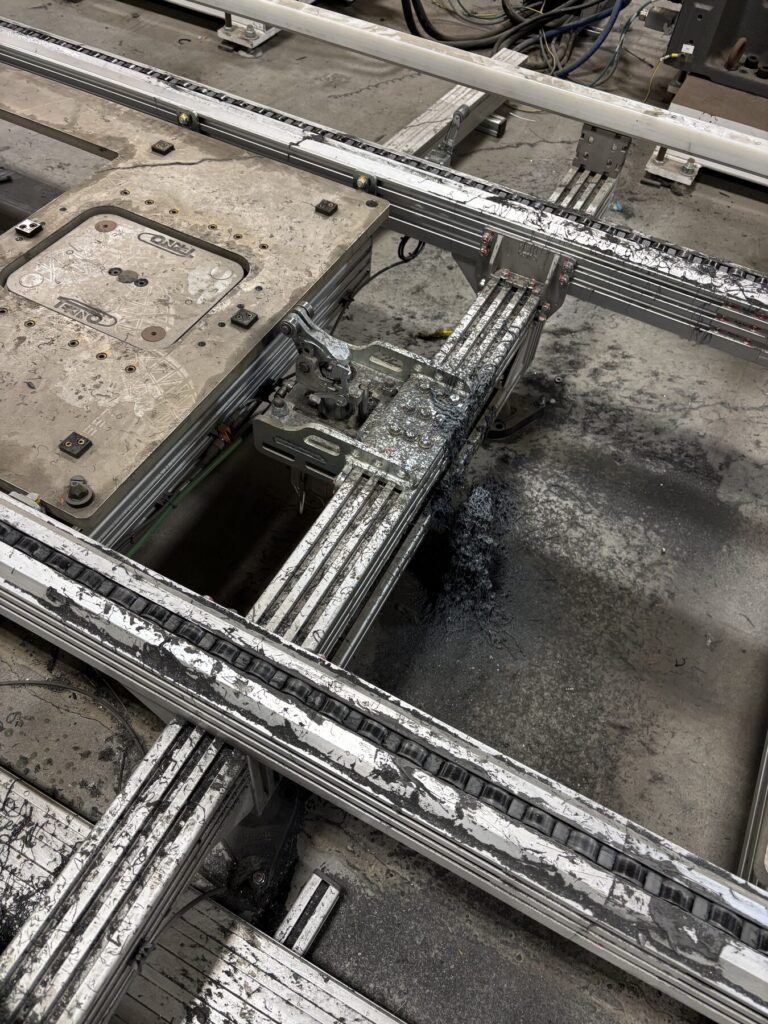 Heavy adhesive stringing on transfer rails and clamp bracket before dry ice blasting, Windsor automotive plant